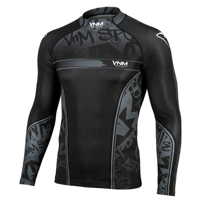A long-sleeve athletic rash guard in black and dark gray with a subtle graffiti-style graphic pattern, featuring the VNM brand logo on the chest and shoulders, shown against a solid black background.